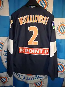 Maillot bleu foncé portant le flocage "Michalowski" et le numéro 2 en orange.