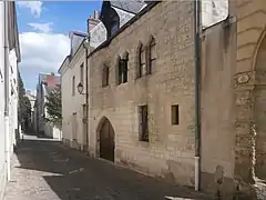 Photographie en couleurs de la façade d'une maison avec des fenêtres à meneau au premier étage.