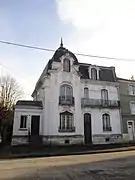 Maison XIXe, architecture éclectique, dissymétrie, comble à la Mansart, cartouche au-dessus des ouvertures, balcon avec ferronnerie.