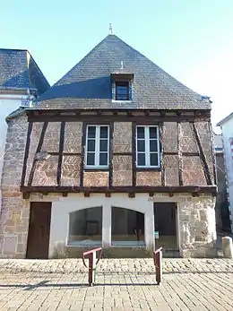 Vue d’une façade de maison avec pans de bois et briques et toit d’ardoises.