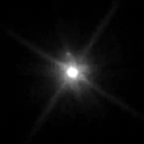 Un gros point blanc lumineux entouré d'une sorte d'aura ; un petit point gris est visible.
