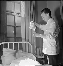 Photographie en noir et blanc d'un infirmier au chevet d'un patient hospitalisé.