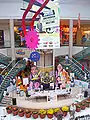 Photo d'intérieur d'un centre commercial présentant une exposition avec des affiches de la série et des fabrications en papier des personnages.