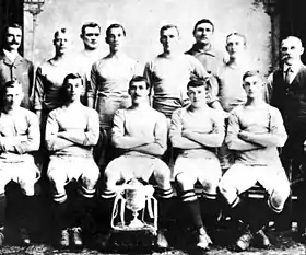 L'équipe de Manchester City en 1904, composée de 13 hommes. Ils posent devant le trophée de la FA Cup. La photo est en noir et blanc.