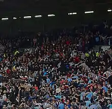 Photo des supporters de Manchester City, en tribune dos tourné au terrain, effectuant la danse du Poznań.