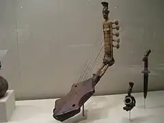 Harpe cintrée à 5 cordes ornée d'une figure anthropomorphe.