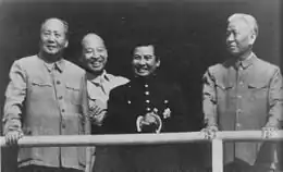 photo noir et blanc sur laquelle on peut voir de gauche à droite Mao Zedong, Peng Zhen (à l’arrière plan), Norodom Sihanouk et Liu Shaoqi ; les dirigeants chinois porte des costumes clairs alors que celui de Sihanouk se distingue par sa teinte proche du noir