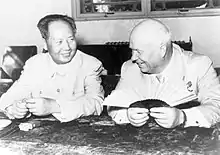 Photographie de deux hommes souriant assis à une table