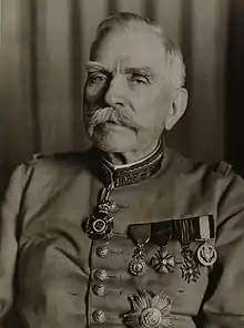 Photographie noir et blanc d'un homme moustachu, âgé, en uniforme militaire. De nombreuses décorations sont visibles sur son torse.