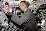 Marc Garneau opèrant le bras canadien Canadarm durant sa deuxième mission, STS-77, à bord de la navette spatiale Endeavour.