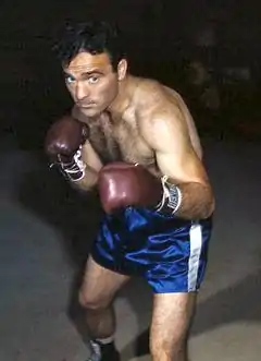 Un homme en position de combat portant des gants et un short de boxe.
