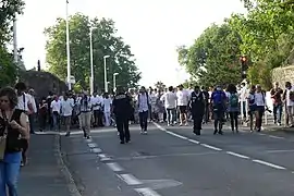 Des centaines de personnes vêtues de blanc, en train de marcher, sur une route.