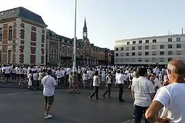 Des centaines de personnes vêtues de blanc, en train de marcher, sur une route.