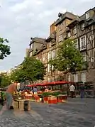 étales d'un marché en ville, bordé de bâtiments à colombages.