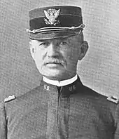 Portrait noir et blanc d'un homme en tenue militaire portant la moustache et coiffé d'une casquette militaire.
