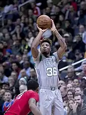 Un joueur de basket-ball saute balle au main et s'apprête à le lancer vers le panier.