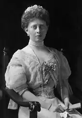 Portrait de trois-quarts d'une jeune femme assise portant un diadème et un long collier de perles.