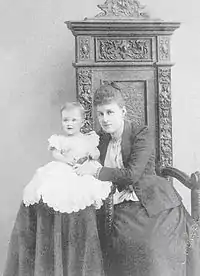 Photographie en noir et blanc montrant un bébé et une femme assis l'un à côté de l'autre.