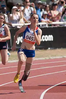 Athlète handisport, avec une prothèse à la jambe gauche, courant dans un virage.