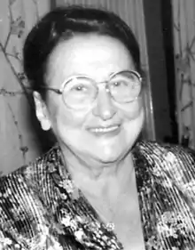 photo en noir et blanc d'une dame souriante, avec lunettes