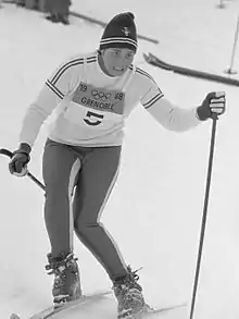 Photographie en noir et blanc d'une skieuse en course portant le dossard no 5