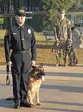 Un homme en uniforme avec un chien en laisse assis à ses pieds