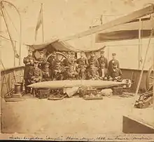 Un groupe de marin prend la pose derrière une torpille sur le pont d'un navire