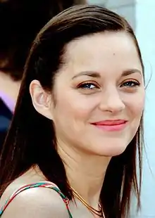 Photographie en couleurs de type portrait d'une femme brune et souriante.