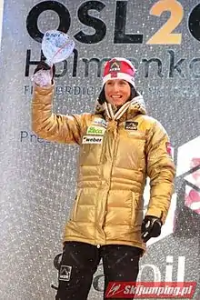 Skieuse sur un podium, levant une coupe en verre de la main droite.