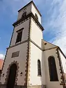 Photographie couleur d'un clocher surmontant une façade d'église.