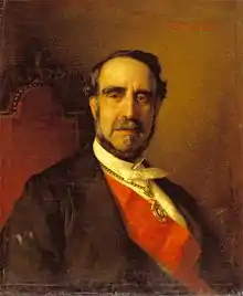 Photo en couleurs du tableau représentant un homme barbu en costume sous le quel il porte une écharpe rouge.