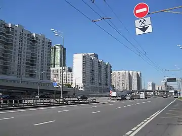 Photo en couleur d'une large avenue bordée d'immeubles de 14 étages.