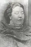 Photographie mortuaire en noir et blanc du visage d'une femme bien en chair.