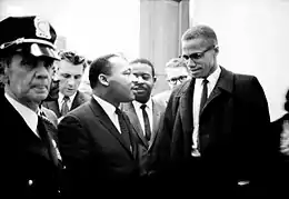 Photographie en noir et blanc en extérieur de Martin Luther King et Malcolm X