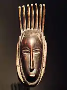 masque anthropomorphe en bois, allongé en hauteur, surmonté d'une coiffure sous forme de bâtons érigés verticalement