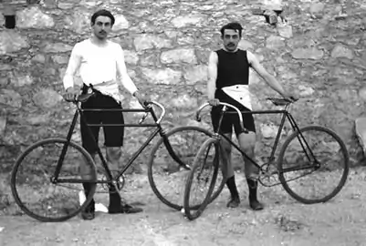 Photo des athlètes français Léon Flameng et Paul Masson, debout, tenant chacun leur vélos.