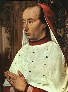Homme en costume rouge et blanc de cardinal, les mains jointes en prière.