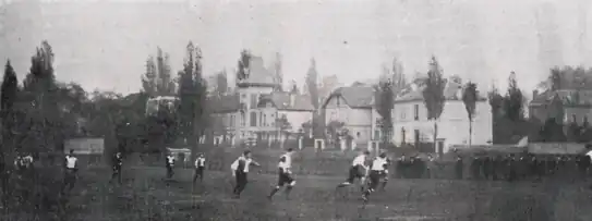 Photo en noir et blanc d'un match de football, des spectateurs au fond à droite