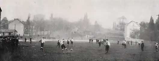 Photo en noir et blanc d'un match de football, des spectateurs à gauche