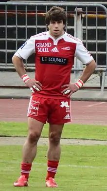 Un joueur de rugby de face, à l'arrêt et les mains sur les hanches