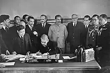 Photo de la signature officielle du traité de non-agession avec Staline observant la cérémonie.