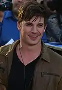 Homme blanc aux cheveux châtains coupés courts et yeux bleus.