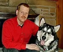 Homme aux cheveux roux posant avec un chien