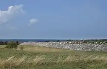 Un long mur traversant le paysage, avec la mer en arrière-plan