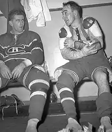 Photographie en noir et blanc de Toe Blake et Maurice Richard en train de discuter dans les vestiaires après un match des Canadiens de Montréal. Richard est situé sur la gauche alors que Blake est à droite de la photo