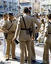 Photo en couleur de plusieurs hommes habillés en gendarmes discutant ensemble, sur une place où il y a foule.