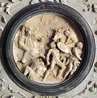 bas-relief circulaire représentant des hommes lors d'une bataille.