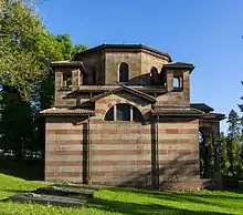 Photographie en couleur d'un petit bâtiment de style néo-roman entouré de tombes