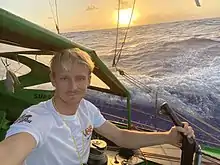 Selfie à l'arrière du bateau, devant un coucher de soleil sur la mer.