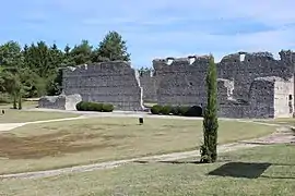 Photographie en couleurs d'un ensemble de hauts murs partiellement ruinés.